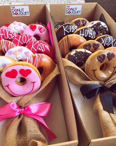 two boxes filled with donuts covered in frosting and decorated with hearts, kiss lips and kisses