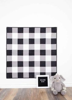 a black and white checkered wall hanging next to a welcome baby sign with an elephant