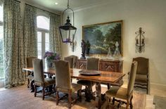 a dining room table with chairs and a painting hanging on the wall behind it in front of a window