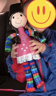 a child holding a stuffed doll with a smiley face on it