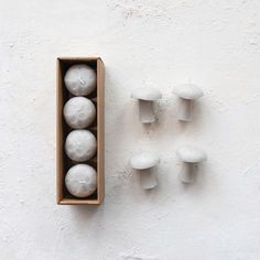 four white candles are in a box on the wall next to them is five smaller ones