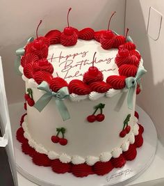 a birthday cake decorated with cherries and ribbons