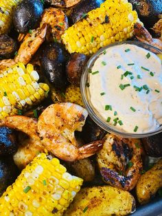 grilled shrimp, corn on the cob and potatoes with ranch dressing in a bowl