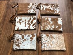 four brown and white cowhide pouches with tassels laid out on the floor