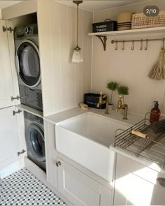 a washer and dryer in a white kitchen with black and white floor tiles