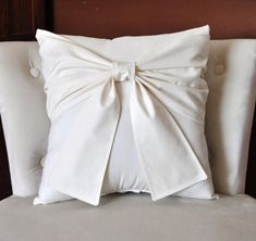 a white pillow with a large bow on it's back sitting on a chair