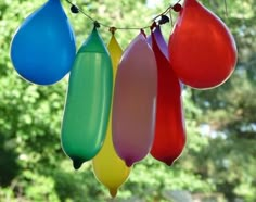 colorful balloons hanging from a string in front of trees