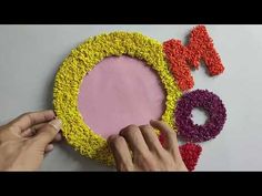 someone is making a flower wreath out of crocheted yarns and felt letters