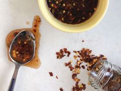 a spoon with some food on it next to a cup and jar filled with something