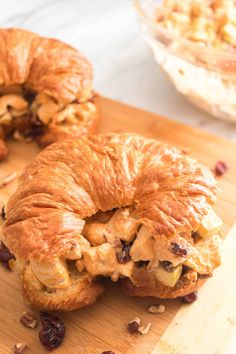 two croissants with chicken and raisins on a wooden cutting board