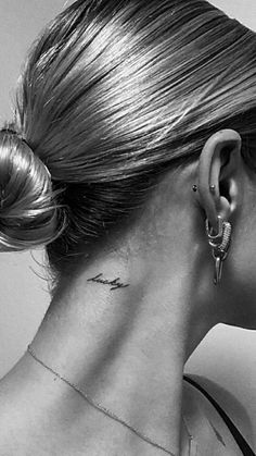 a woman with a tattoo on her neck and behind her ear is looking to the side