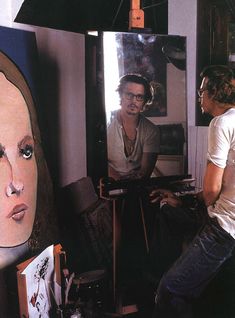 two men are sitting in front of a mirror with an image of a woman on it