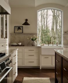 a kitchen with an arched window and white cabinets, wood flooring, and wooden counter tops