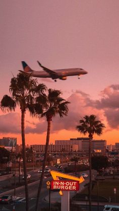 an airplane is flying over a burger restaurant sign and palm trees in the foreground