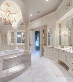 a large bathroom with two sinks, tub and chandelier