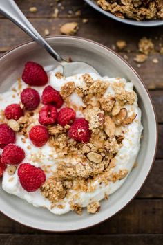 a bowl filled with yogurt, granola and raspberries