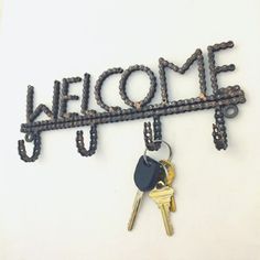 a welcome sign with keys hanging from it's side and the word welcome written on top