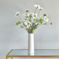 a white vase filled with flowers on top of a glass table