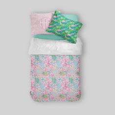 a bed with pink, blue and green floral comforters on top of each other