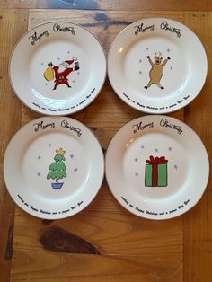 four plates with christmas designs on them sitting on a wooden floor next to each other