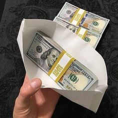 a person is holding two bundles of money in a paper boat with one dollar bill sticking out of it