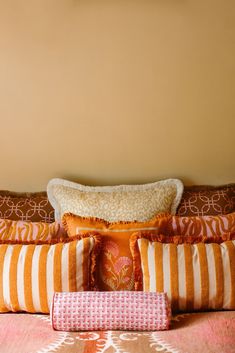 a bed with orange and white pillows on top of it next to a brown wall