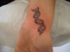 a woman's wrist with a tattoo on it that has a spiral design in the middle