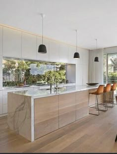 an open kitchen and dining area with wood flooring, white walls, and large windows