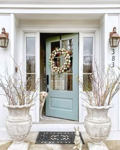 the front door is decorated with wreaths and potted plants