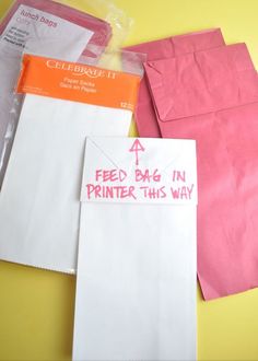 some pink and white envelopes sitting on top of a yellow table next to each other