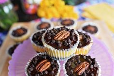 cupcakes with chocolate frosting and pecans are on a purple platter