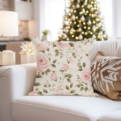 a living room with a christmas tree in the background and pillows on the couches