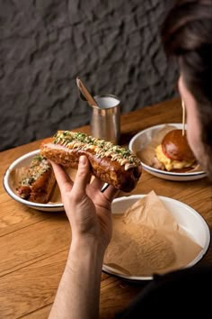 a person sitting at a table with two plates of food and a sandwich in front of them