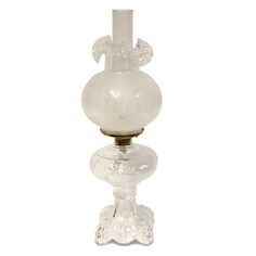 a white glass vase sitting on top of a table next to a candle holder in the shape of a flower