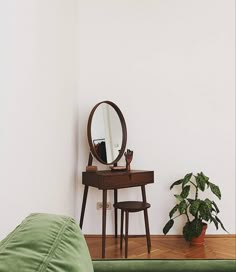 a small table with a mirror, stool and potted plant