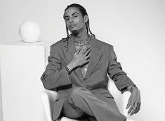 a man sitting on top of a white chair wearing a suit and green socks with his hands in his pockets