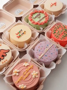 twelve decorated cupcakes in trays on a white surface with the words happy birthday written on them