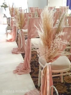 the aisle is lined with chairs and decorated with pink sashes, pamodia