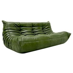 a green leather couch sitting on top of a white floor