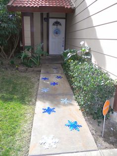 a small house with a white front door and blue snowflakes on the sidewalk