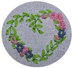 an embroidered heart with pink and blue flowers in the shape of a wreath on a gray background