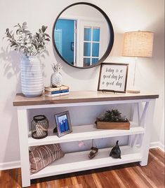 a white table with a mirror and vases on it next to a wooden floor