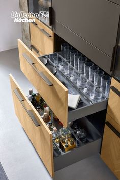 an open drawer in a kitchen filled with bottles and glasses