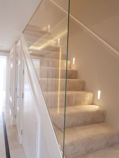 a white staircase with glass railing and lights