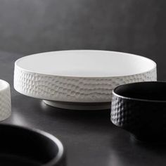 three black and white plates sitting on top of a table next to eachother