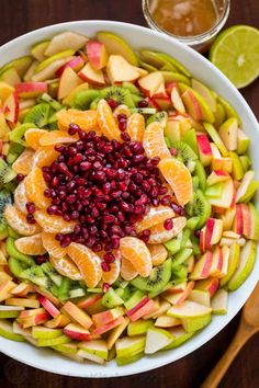 a white bowl filled with fruit and topped with pomegranate