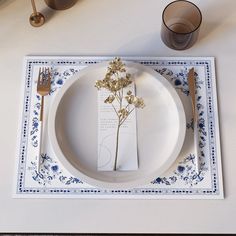 a white plate topped with a flower next to a fork and knife on top of a table