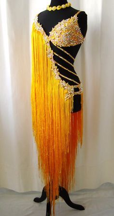 a mannequin dressed in an orange and gold fringed dress with beads on it