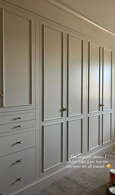 an empty room with many white cabinets and drawers on the wall next to a window