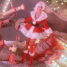 two women dressed as santa clause and mrs claus in front of a christmas tree with lights